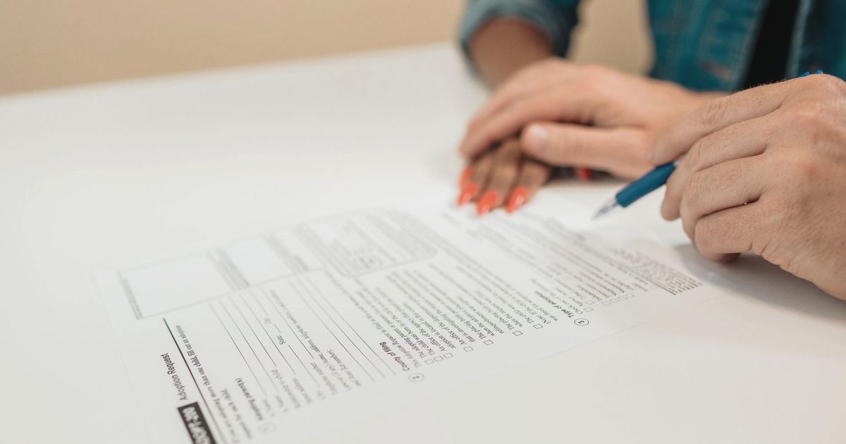Close-up of hands signing adoption papers in an office environment, symbolizing family and legal process.