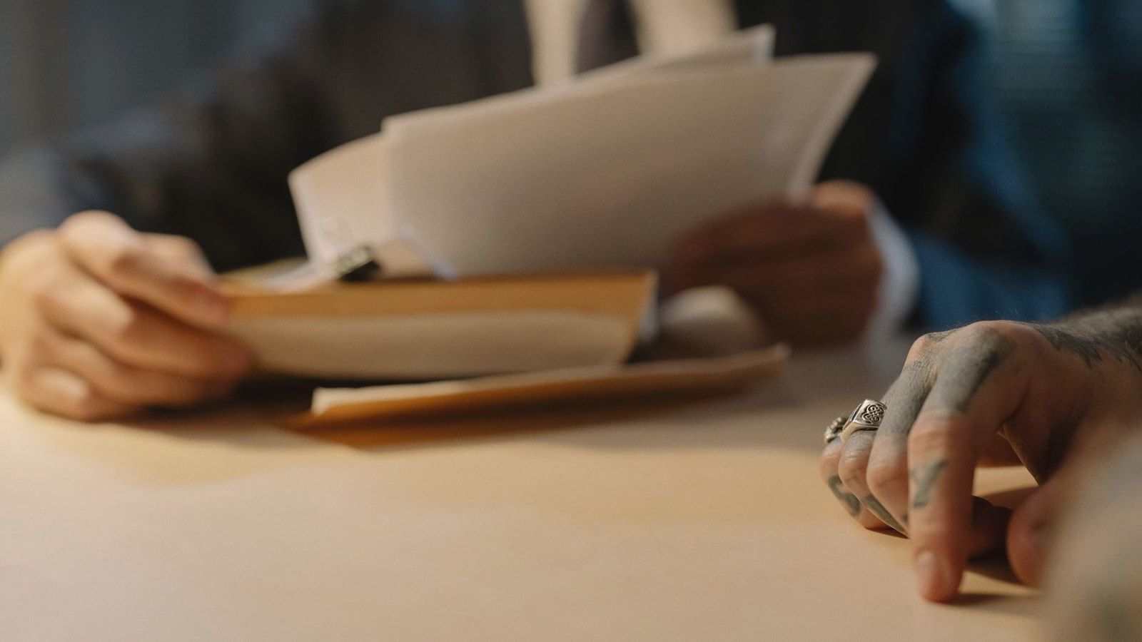 Close-up of business people reviewing documents at a desk, focused on hands and paperwork.