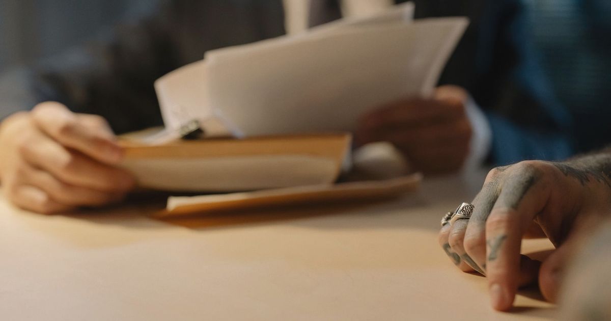 Close-up of business people reviewing documents at a desk, focused on hands and paperwork.