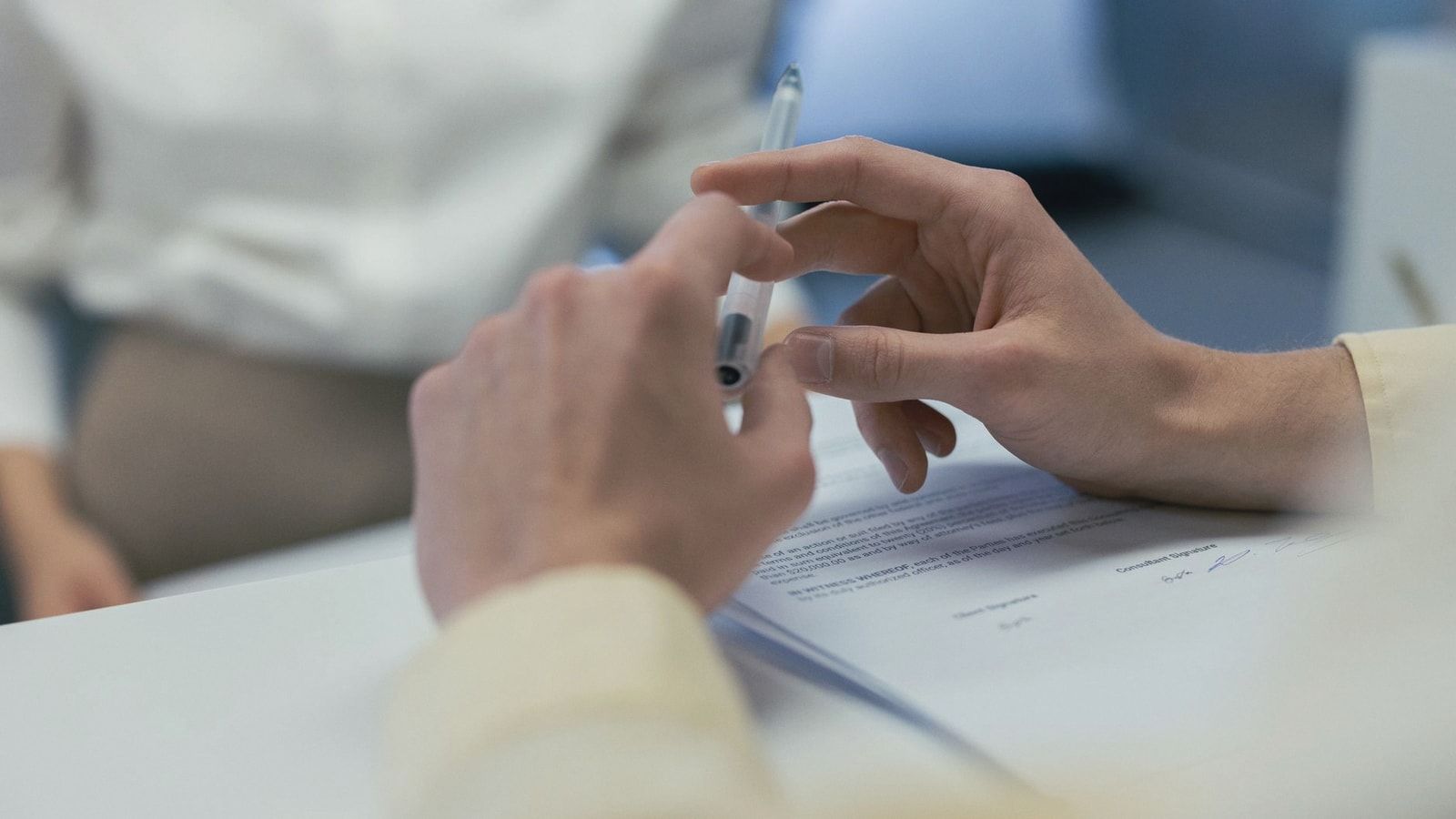 Close-up of hands holding a pen during a business meeting or contract signing.