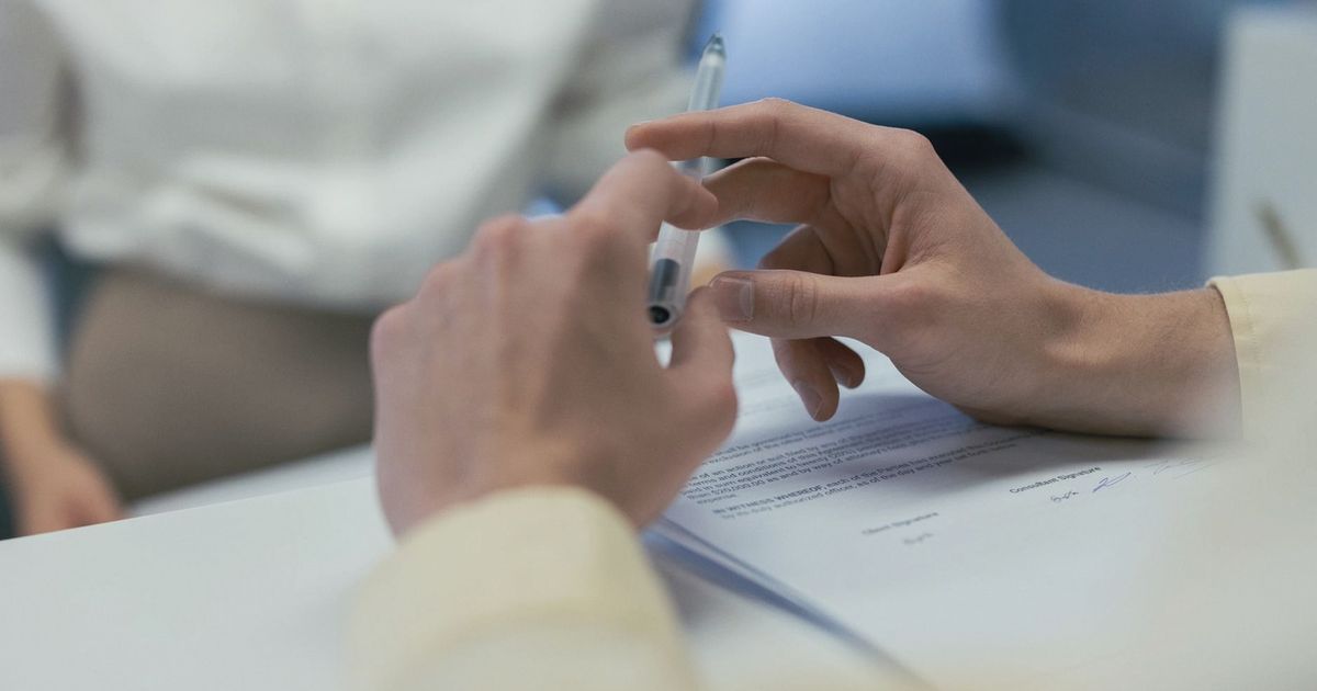 Close-up of hands holding a pen during a business meeting or contract signing.