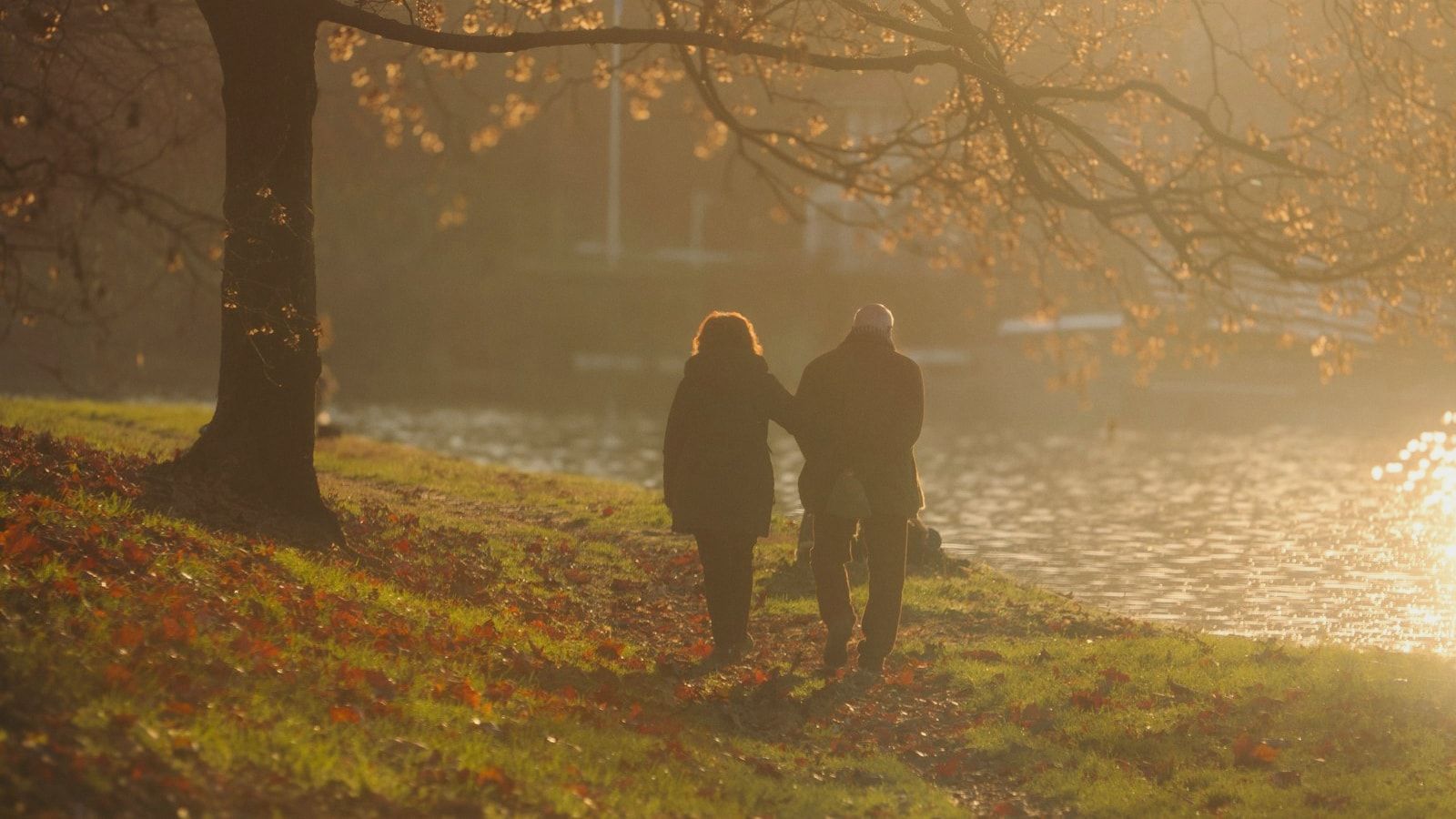 Couple walking by a river at sunset