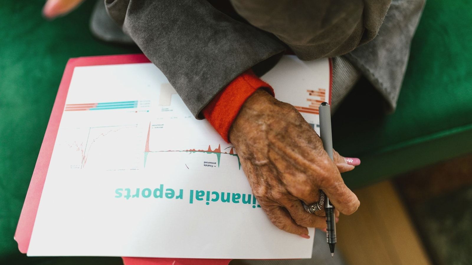 Close-up of an elderly woman holding a pen with a financial report.