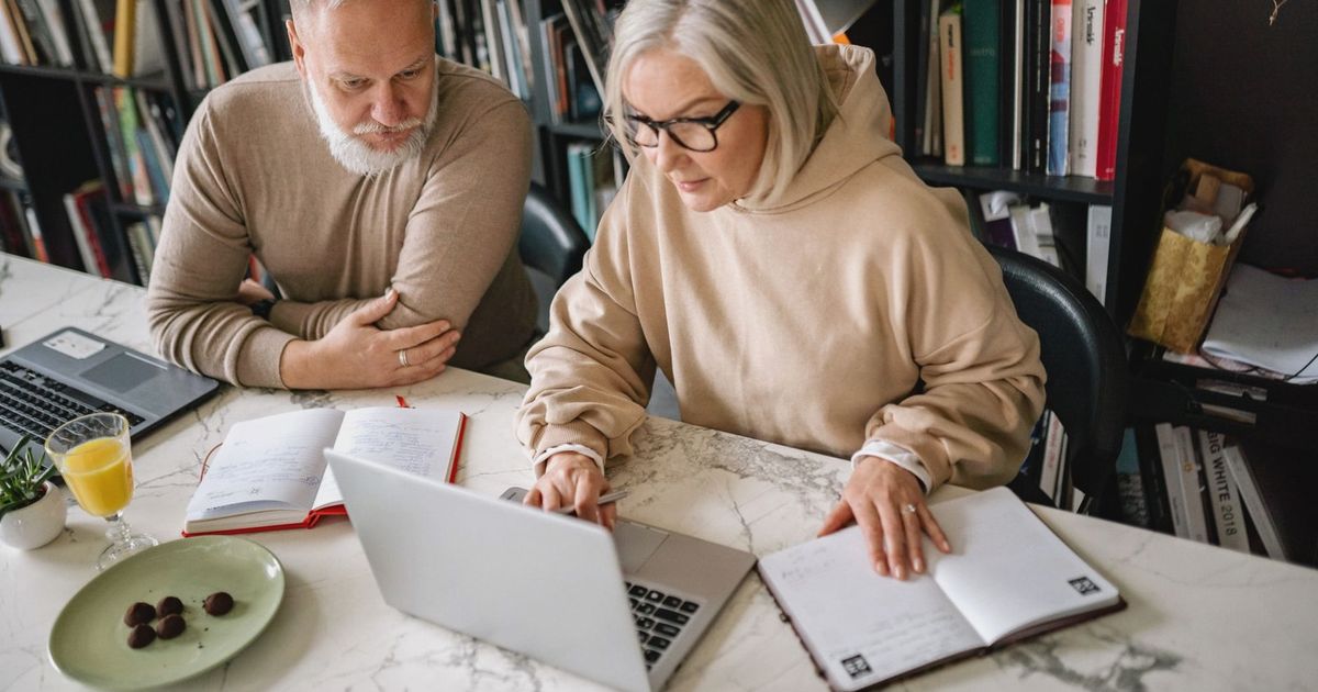 Elderly couple collaborating on laptops in a cozy home office setting.