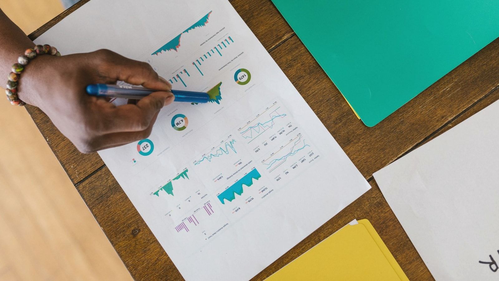 Overhead view of a person analyzing business charts and graphs on paper.