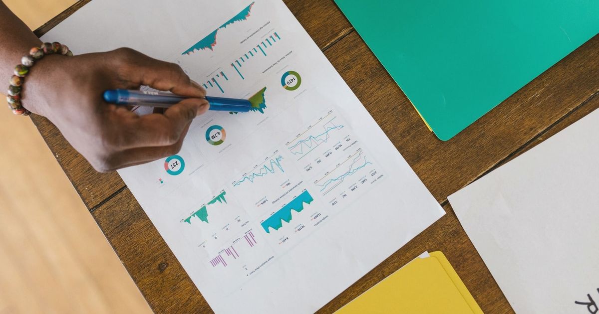 Overhead view of a person analyzing business charts and graphs on paper.