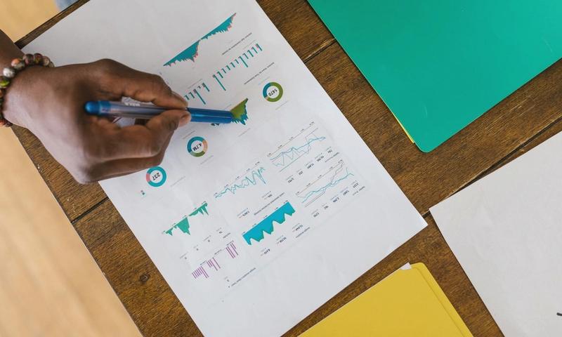 Overhead view of a person analyzing business charts and graphs on paper.