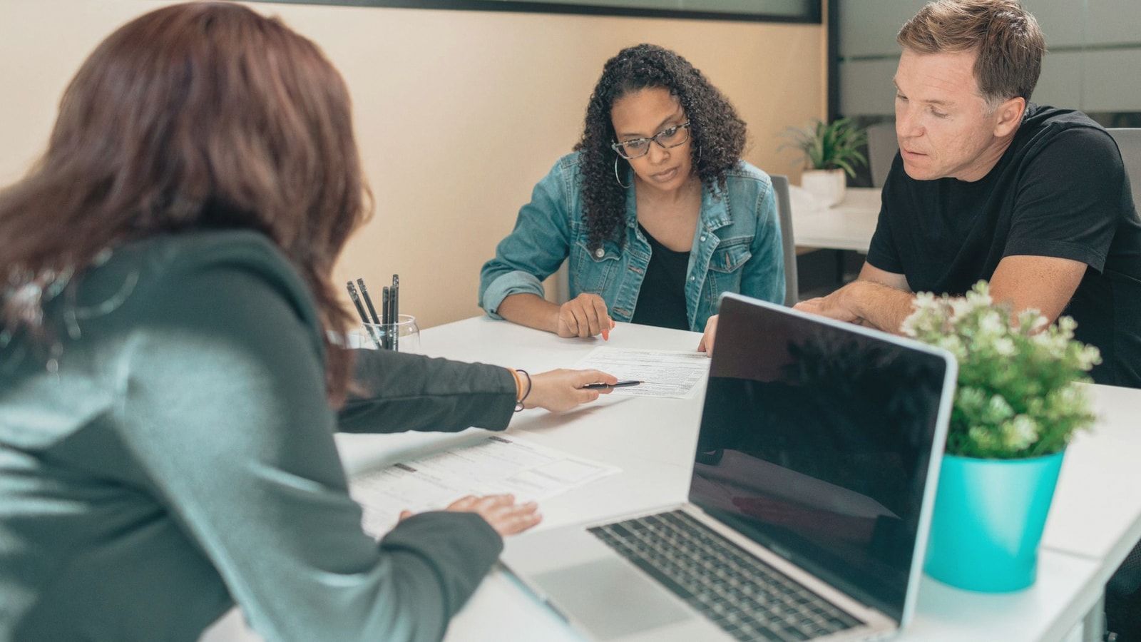 Couple meeting with advisor for adoption process in a modern office setting.