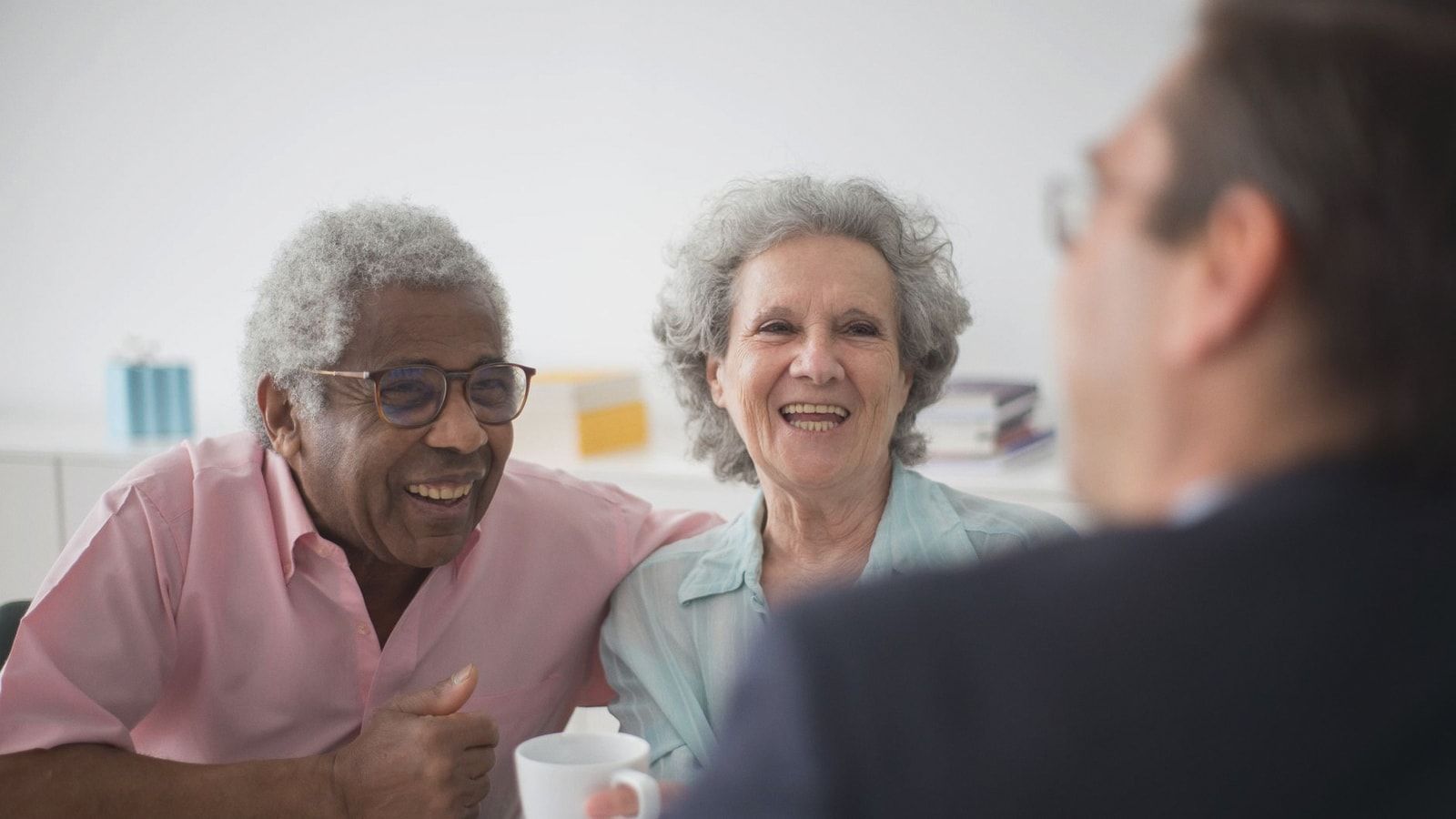 Happy elderly couple enjoying a conversation with a professional advisor indoors.