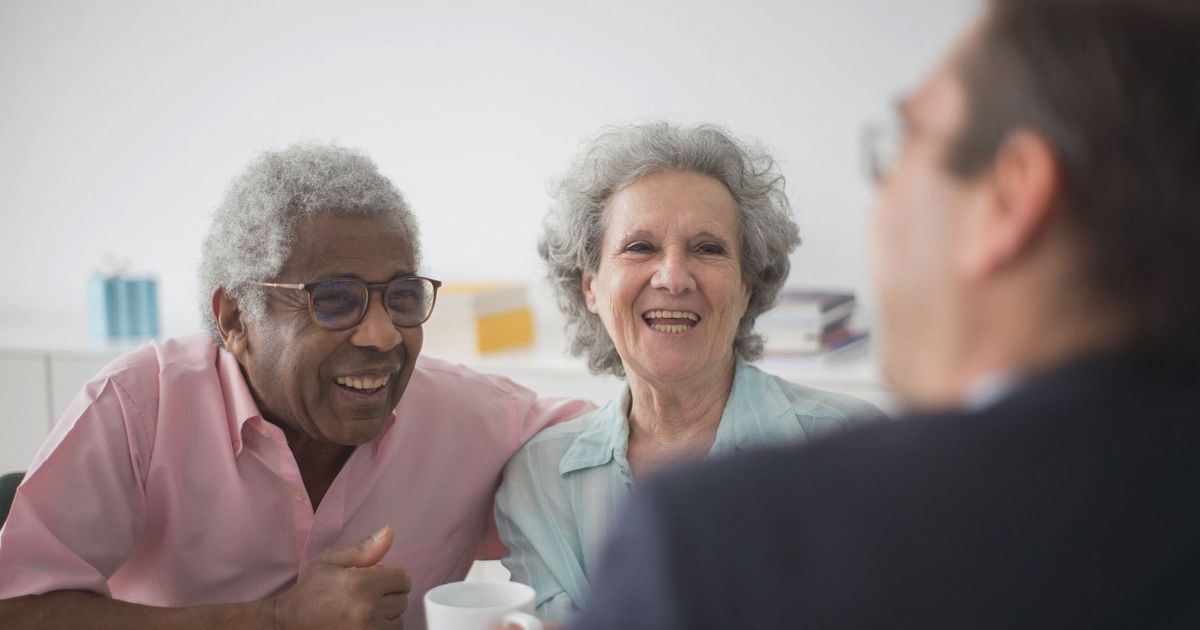 Happy elderly couple enjoying a conversation with a professional advisor indoors.
