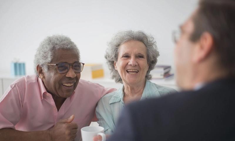Happy elderly couple enjoying a conversation with a professional advisor indoors.