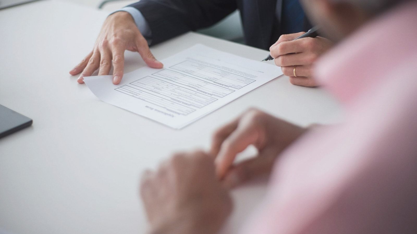 Two professionals engaging in a business meeting, signing documents for a consulting agreement.