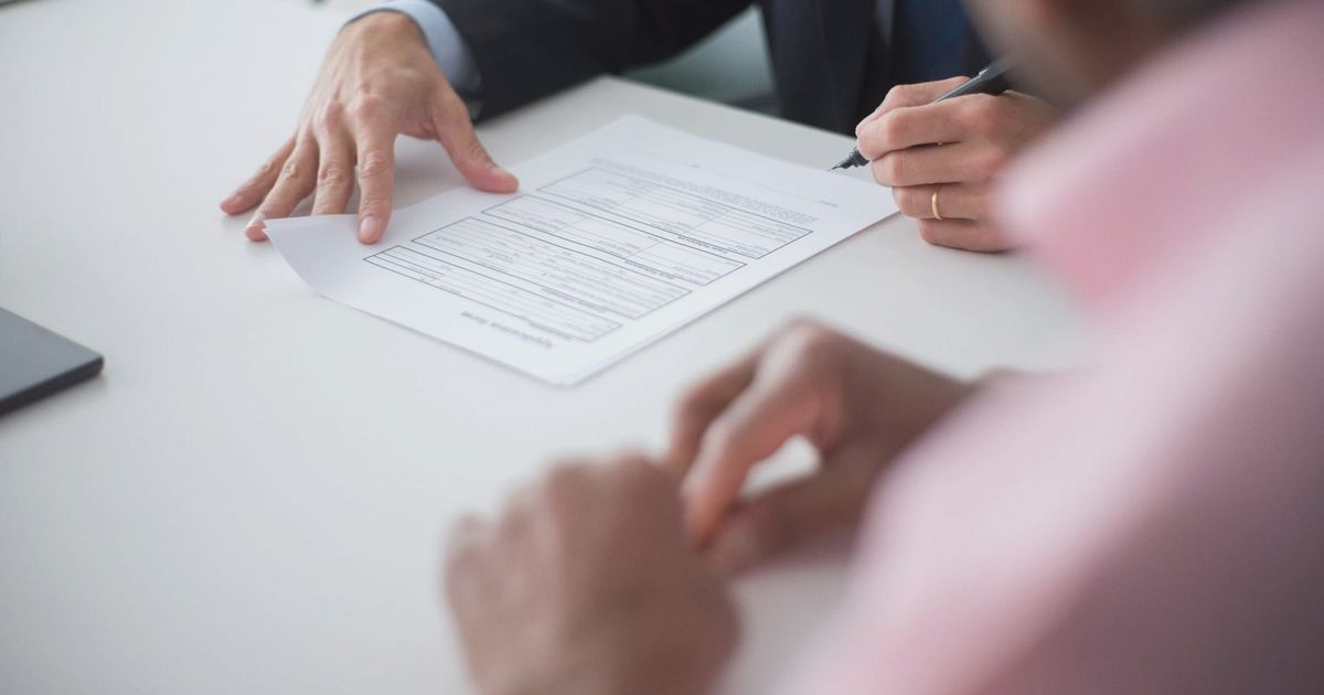 Two professionals engaging in a business meeting, signing documents for a consulting agreement.