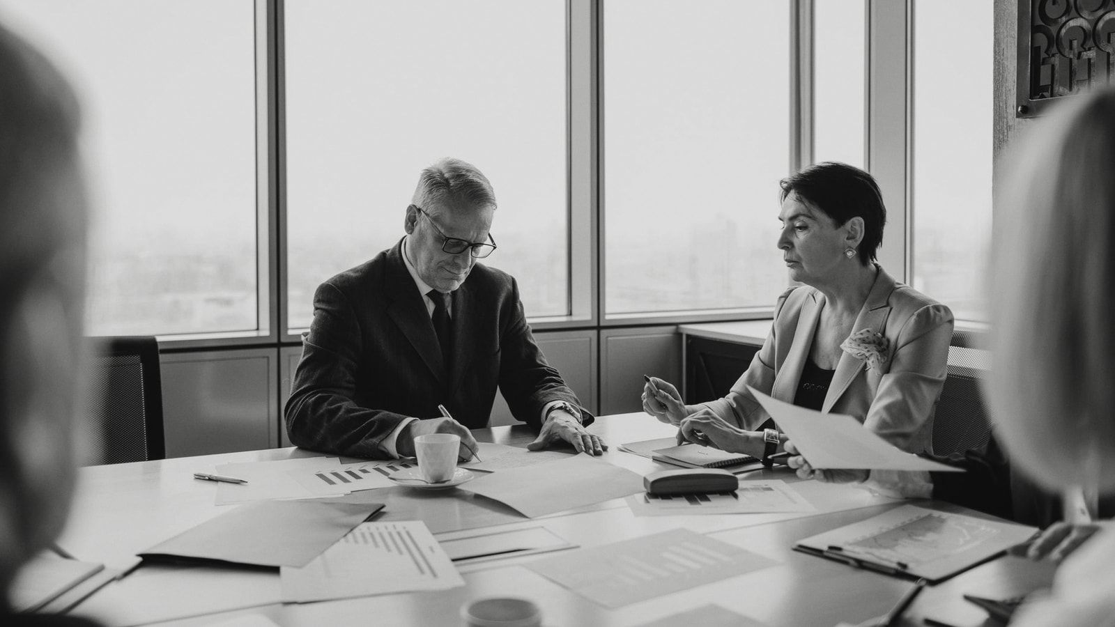 Black and white image of a business meeting with diverse professionals collaborating.