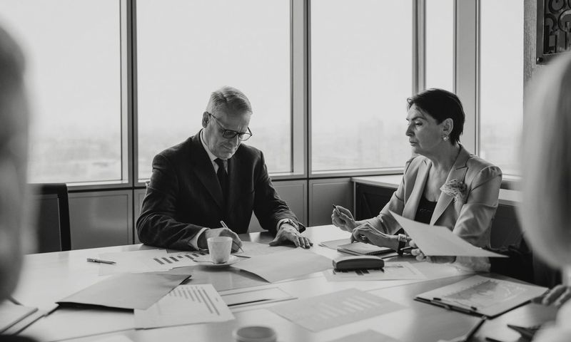 Black and white image of a business meeting with diverse professionals collaborating.
