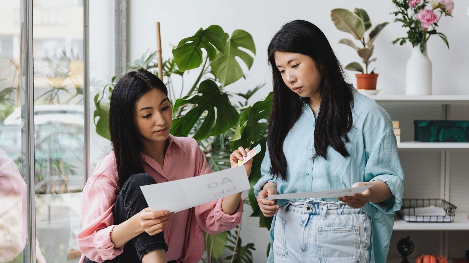 Two women collaborate in a stylish office space, reviewing design concepts.