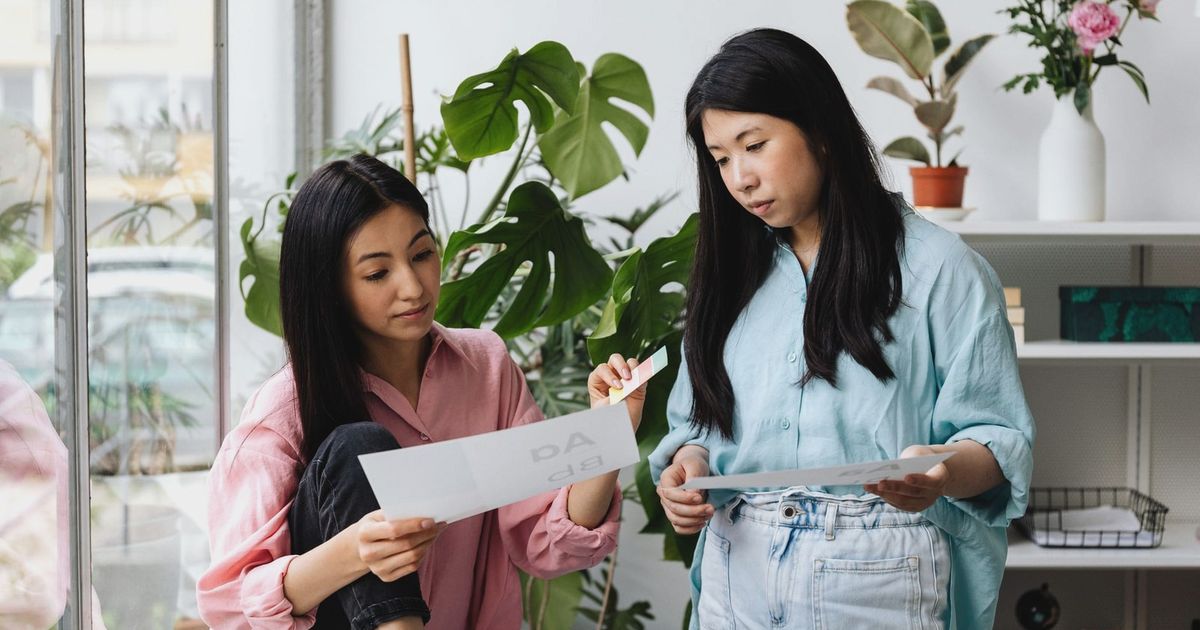 Two women collaborate in a stylish office space, reviewing design concepts.