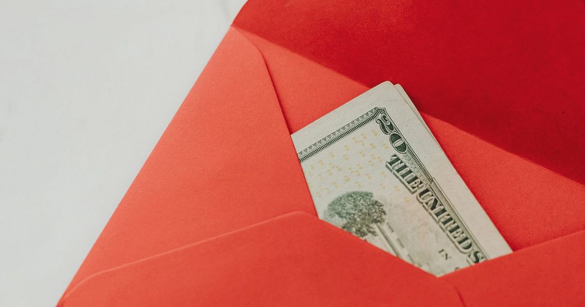 A red envelope containing U.S. dollar bills, symbolizing wealth and gifting.