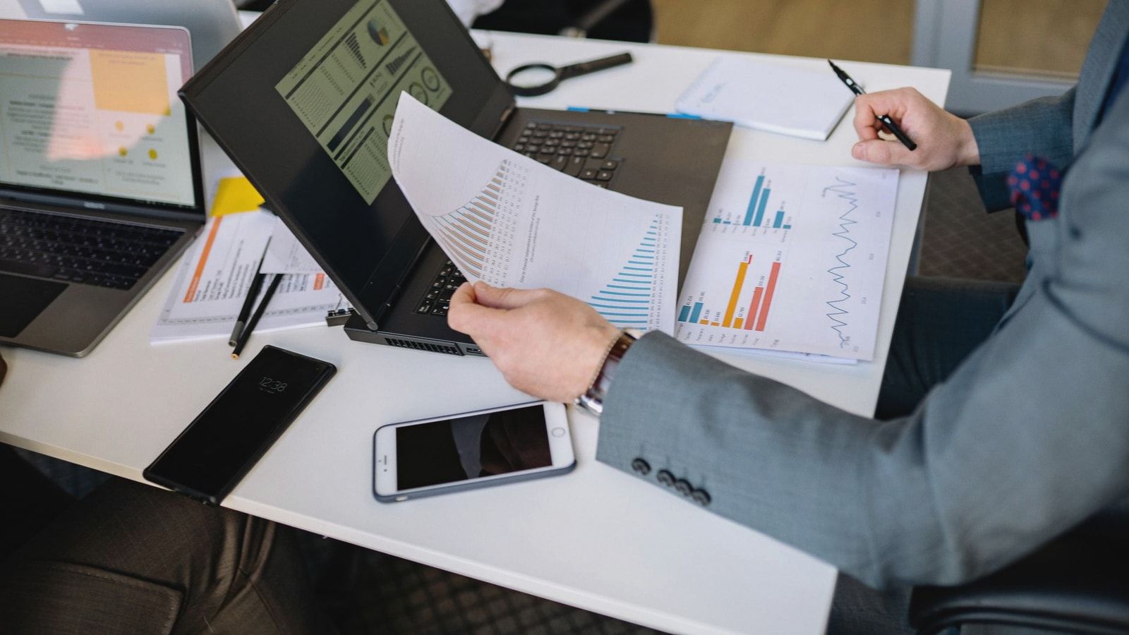 Professionals analyzing charts and graphs on laptops during a business meeting.