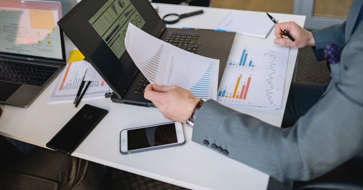 Professionals analyzing charts and graphs on laptops during a business meeting.