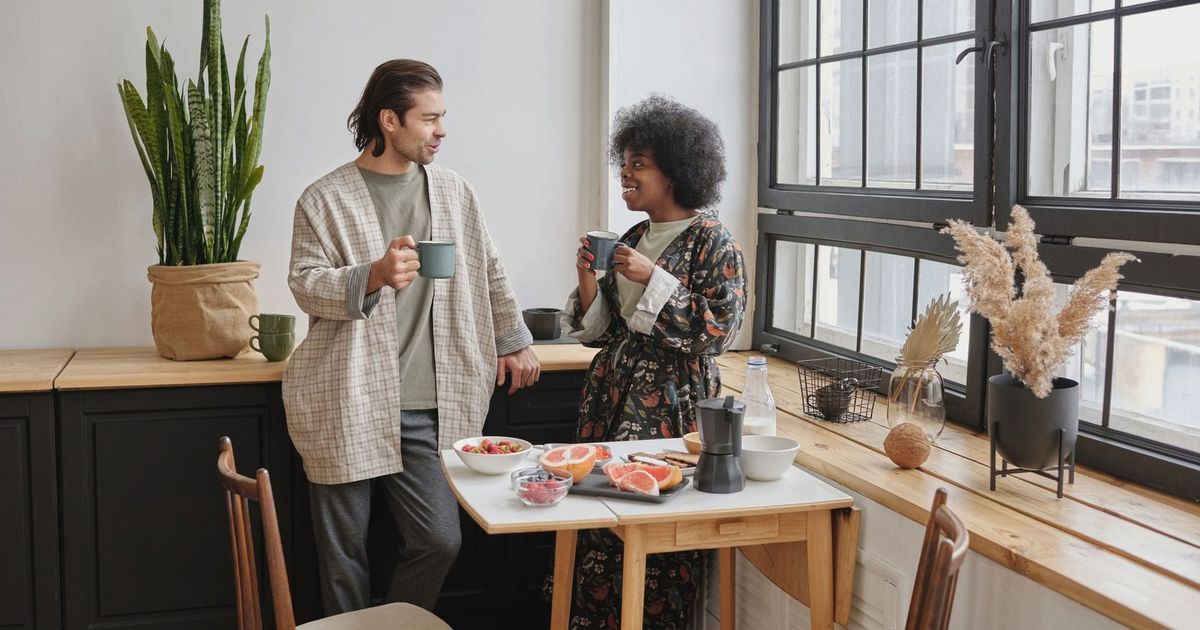 A joyful couple enjoys a morning coffee and healthy breakfast of grapefruit in their cozy apartment.