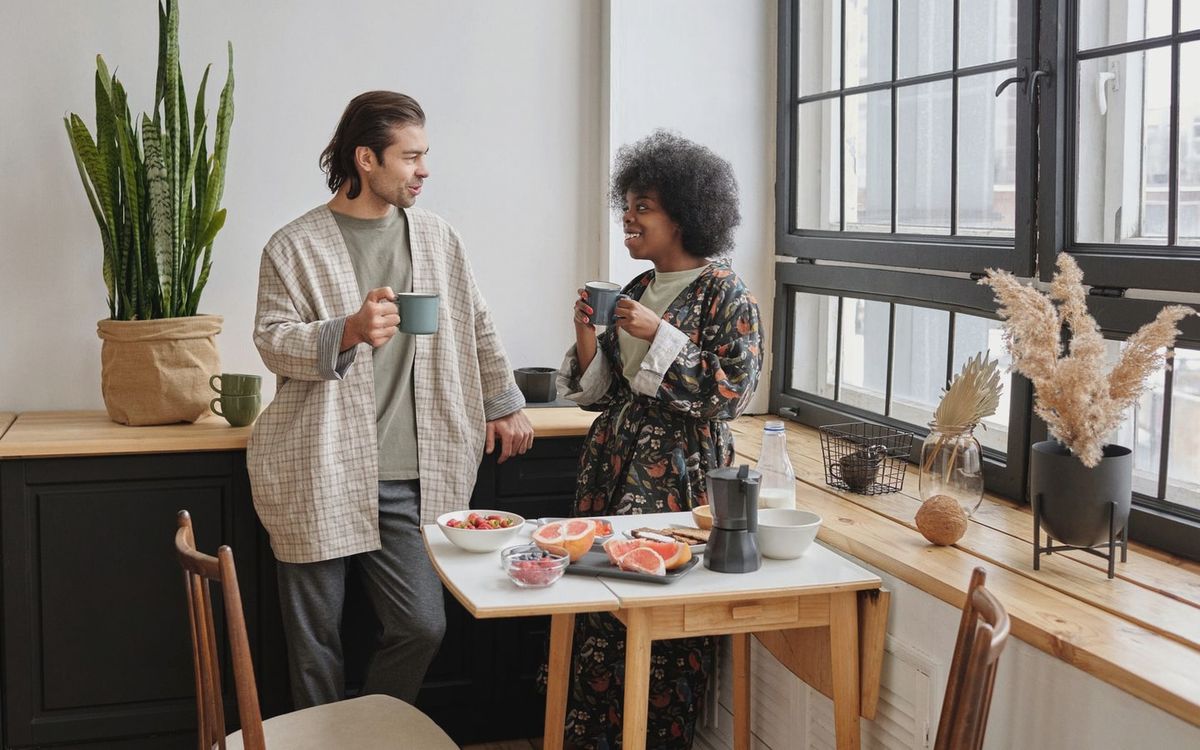 A joyful couple enjoys a morning coffee and healthy breakfast of grapefruit in their cozy apartment.