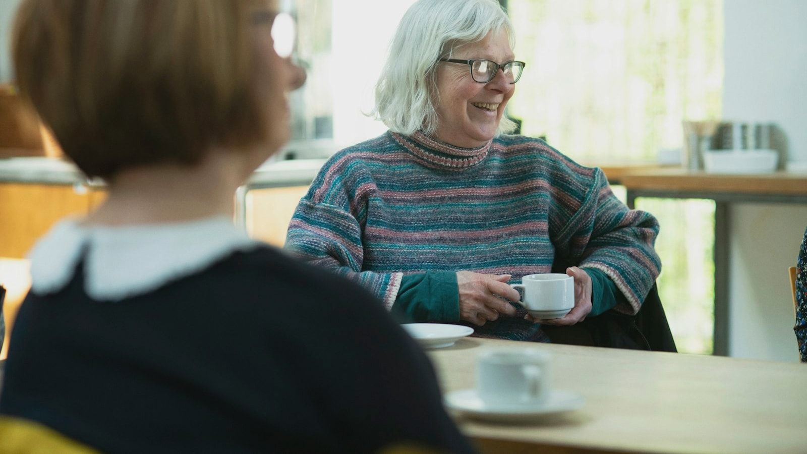 a woman sitting at a table with a cup of coffee