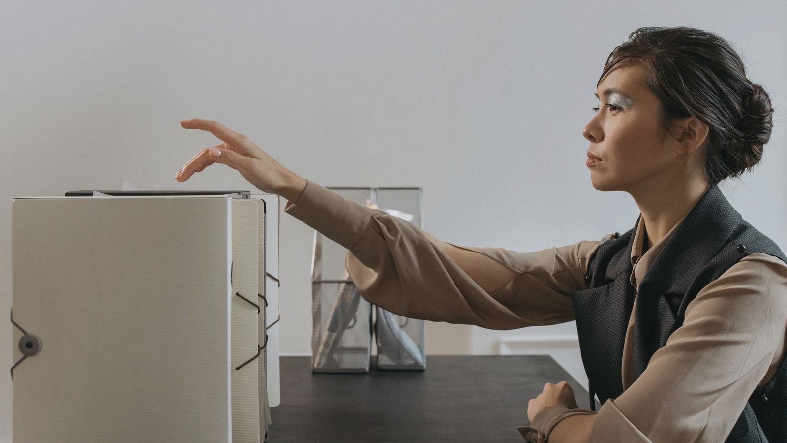 Asian woman efficiently organizing documents at an office desk.