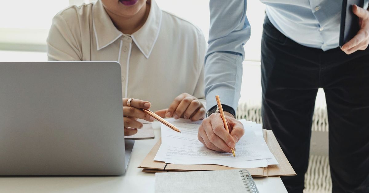 Two colleagues collaborate on paperwork during an office meeting.