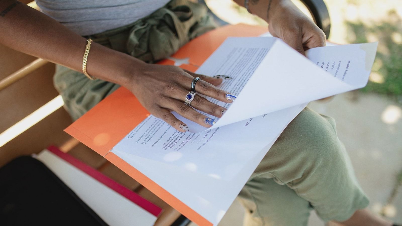 Close-up of a woman checking documents on a bench in natural light.