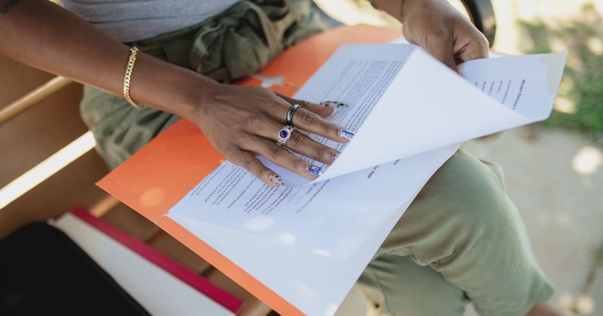 Close-up of a woman checking documents on a bench in natural light.