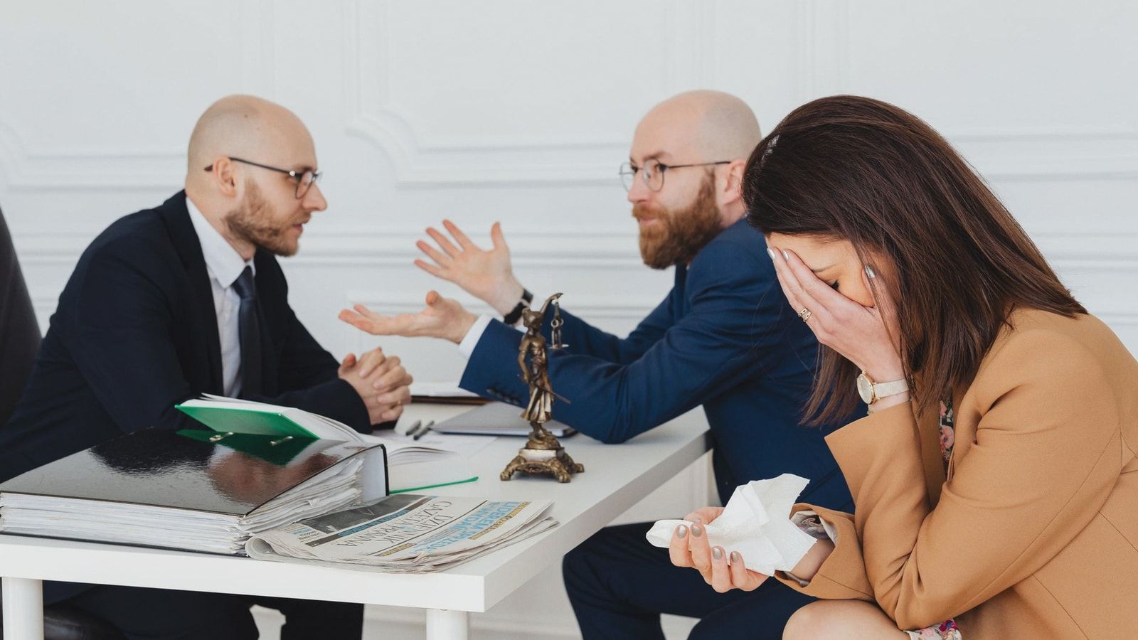 A lawyer mediates an emotional settlement discussion with a distressed couple in a legal office.