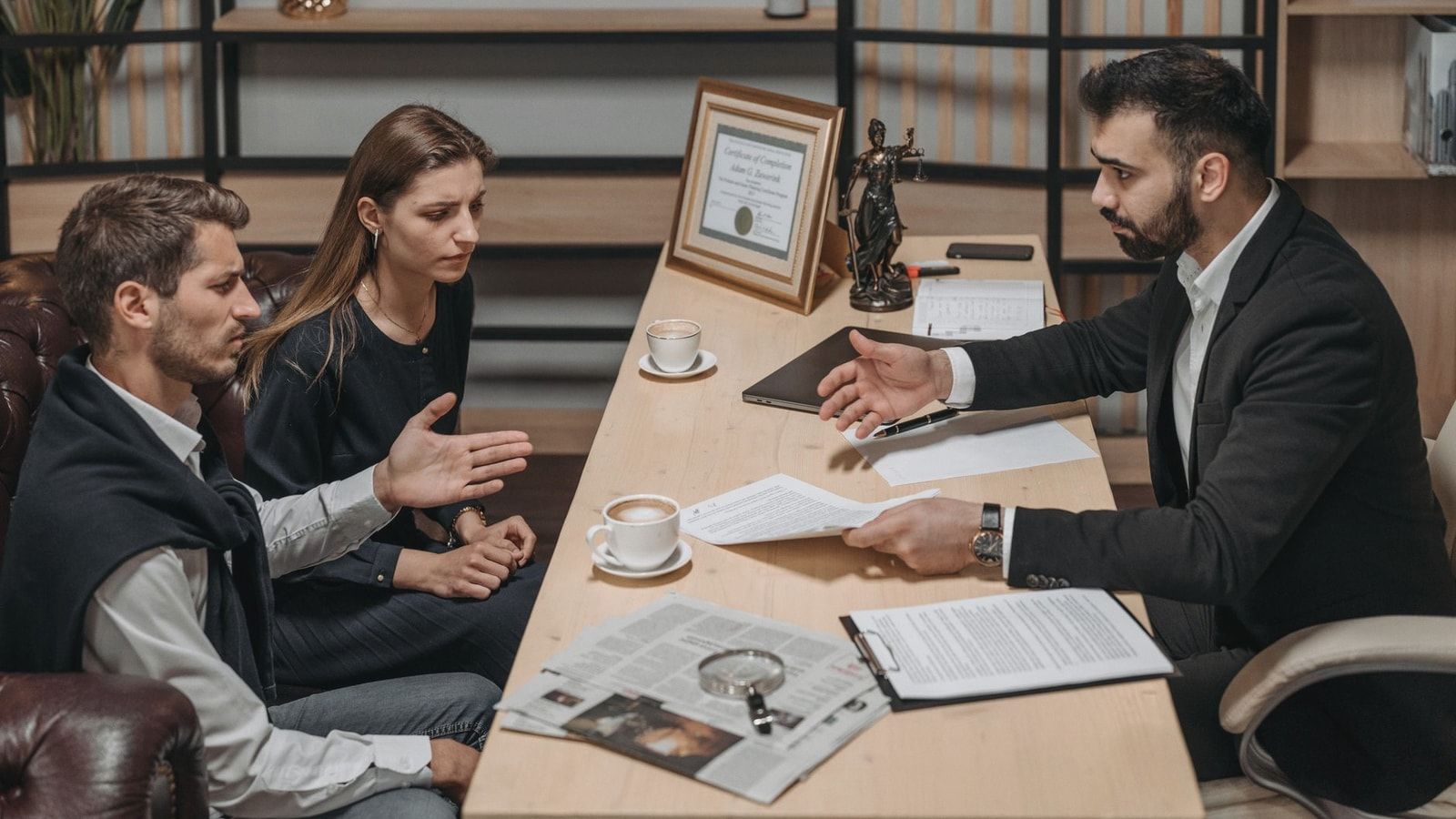 Lawyer consulting clients in an office. Documents and coffee on the table.