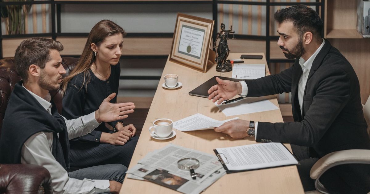Lawyer consulting clients in an office. Documents and coffee on the table.