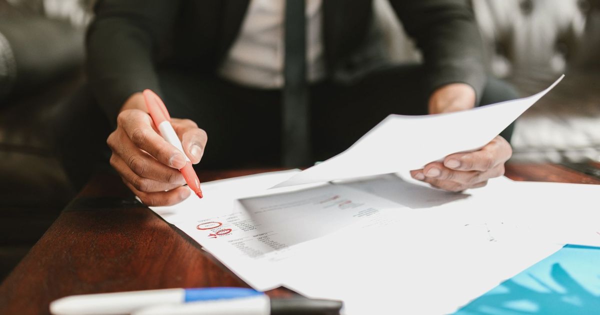 Businessman working with financial documents at office desk, highlighting details.