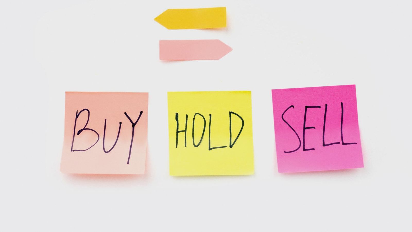 Colorful sticky notes with financial terms 'Buy', 'Hold', and 'Sell' on a clean white backdrop.