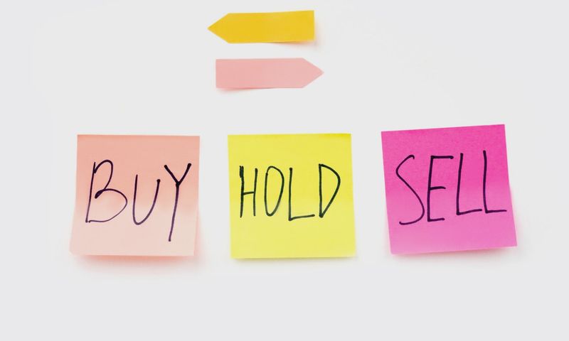 Colorful sticky notes with financial terms 'Buy', 'Hold', and 'Sell' on a clean white backdrop.