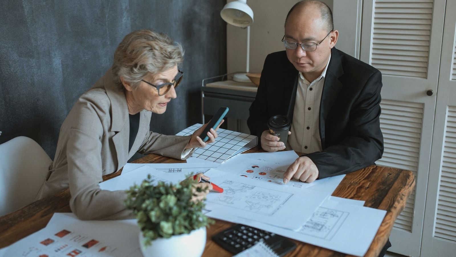 Diverse team of professionals working on project plans at a desk. Collaborative business environment.