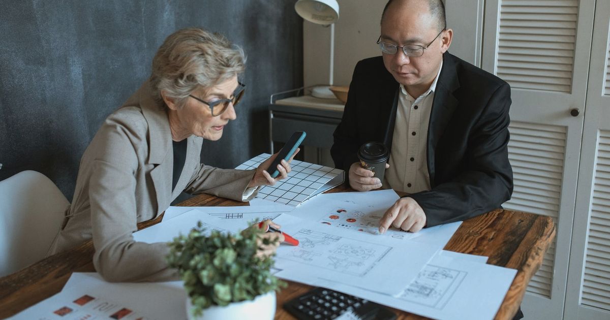 Diverse team of professionals working on project plans at a desk. Collaborative business environment.