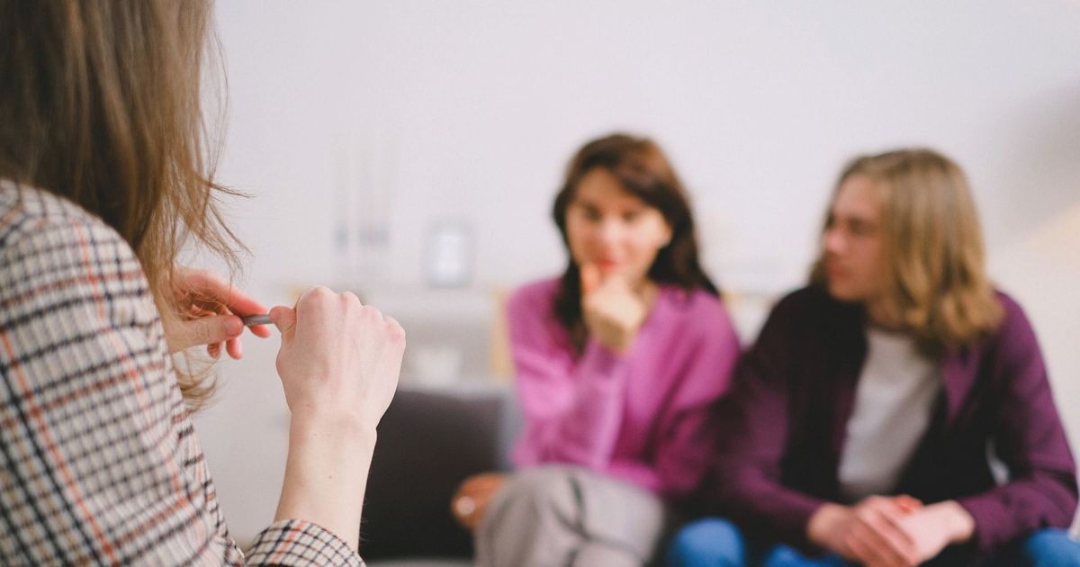 A couple in therapy, guided by a professional therapist in a calm setting.