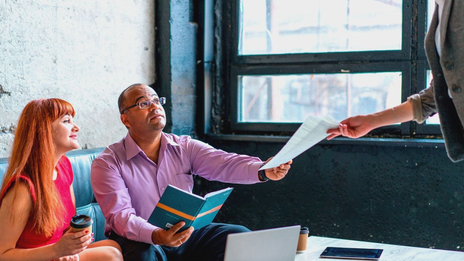 A group of professionals working together in a modern office setting, exchanging documents and ideas.