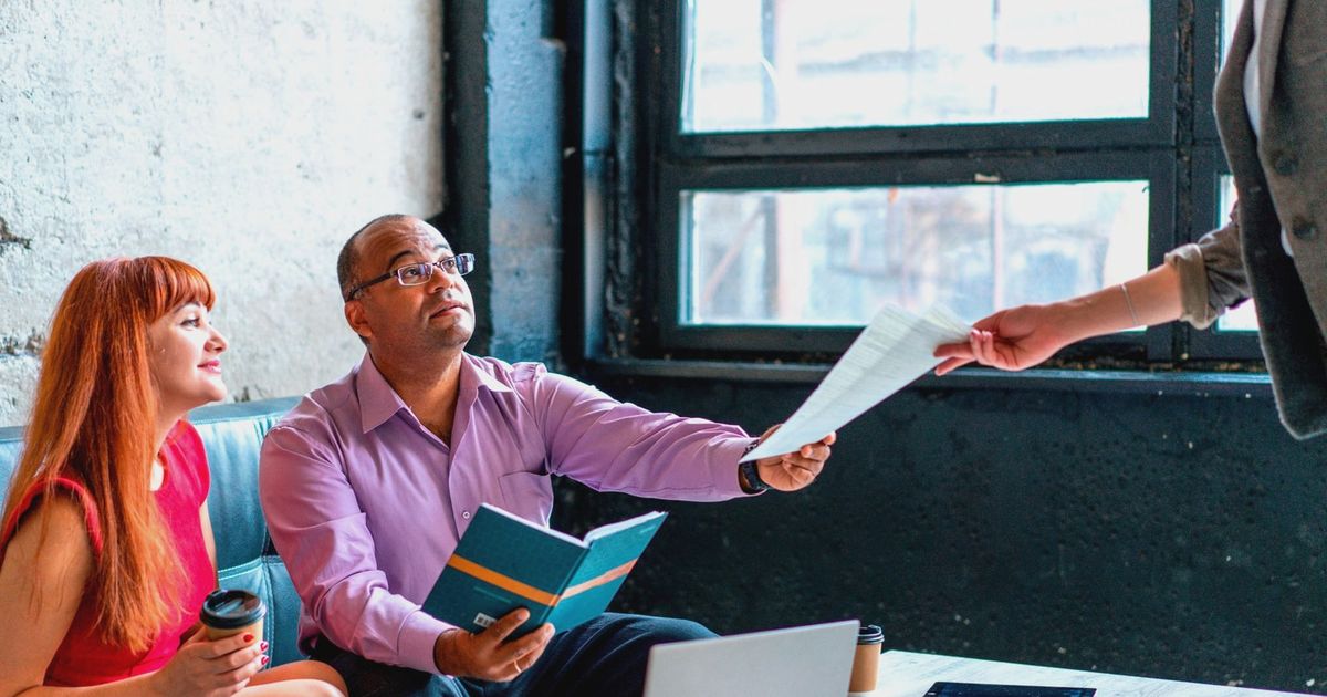 A group of professionals working together in a modern office setting, exchanging documents and ideas.