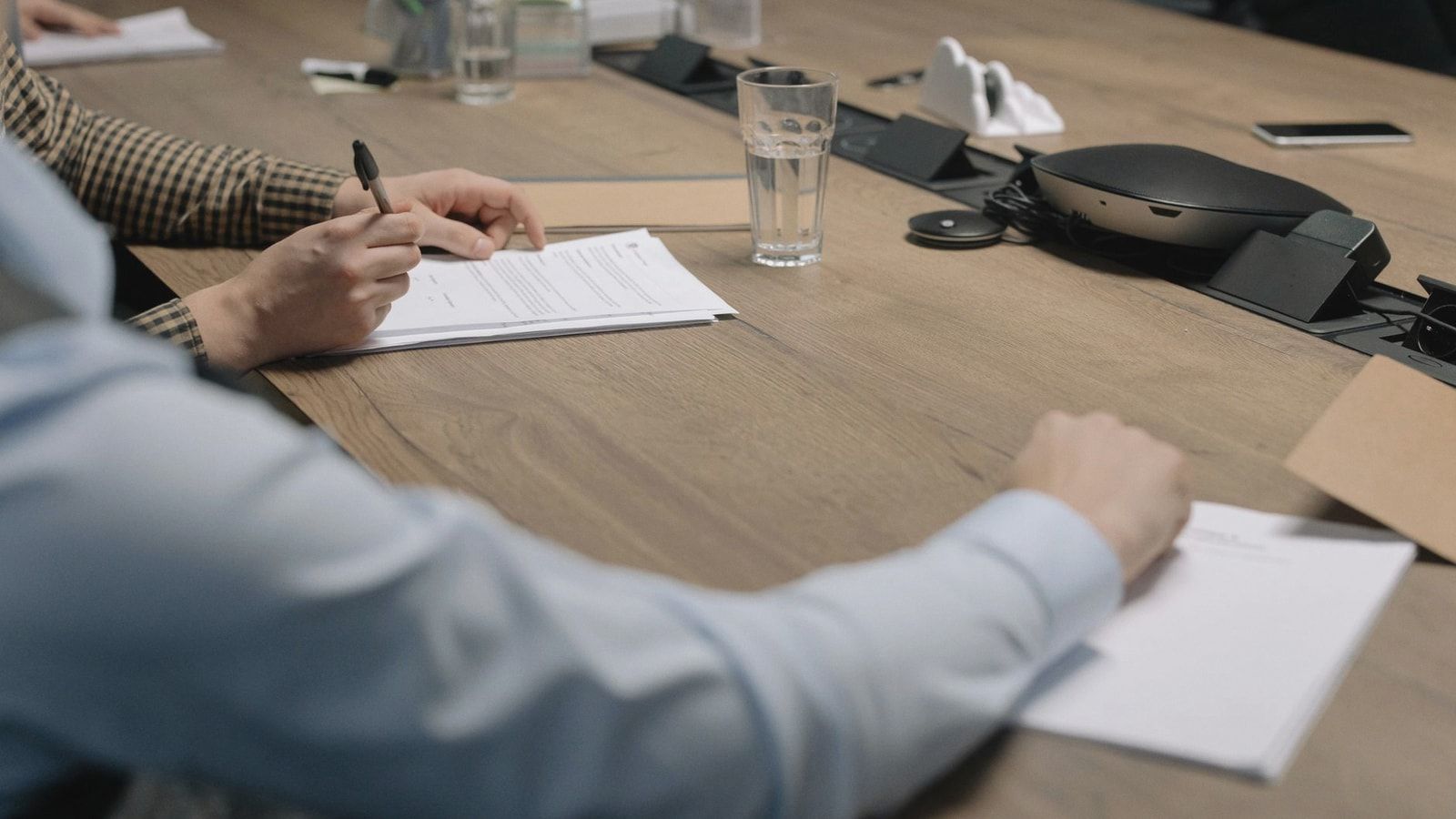 Professional setting of a business meeting with individuals signing documents on a conference table.