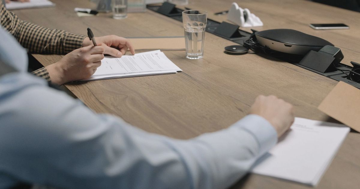 Professional setting of a business meeting with individuals signing documents on a conference table.