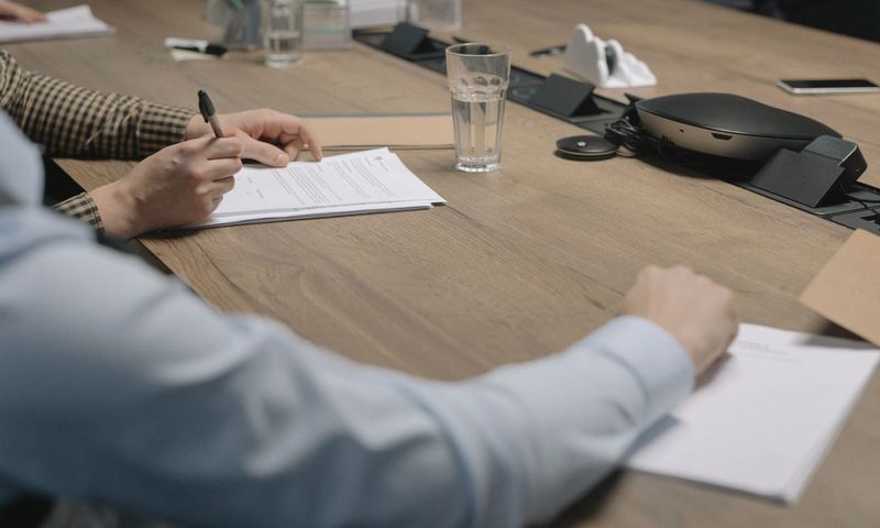 Professional setting of a business meeting with individuals signing documents on a conference table.