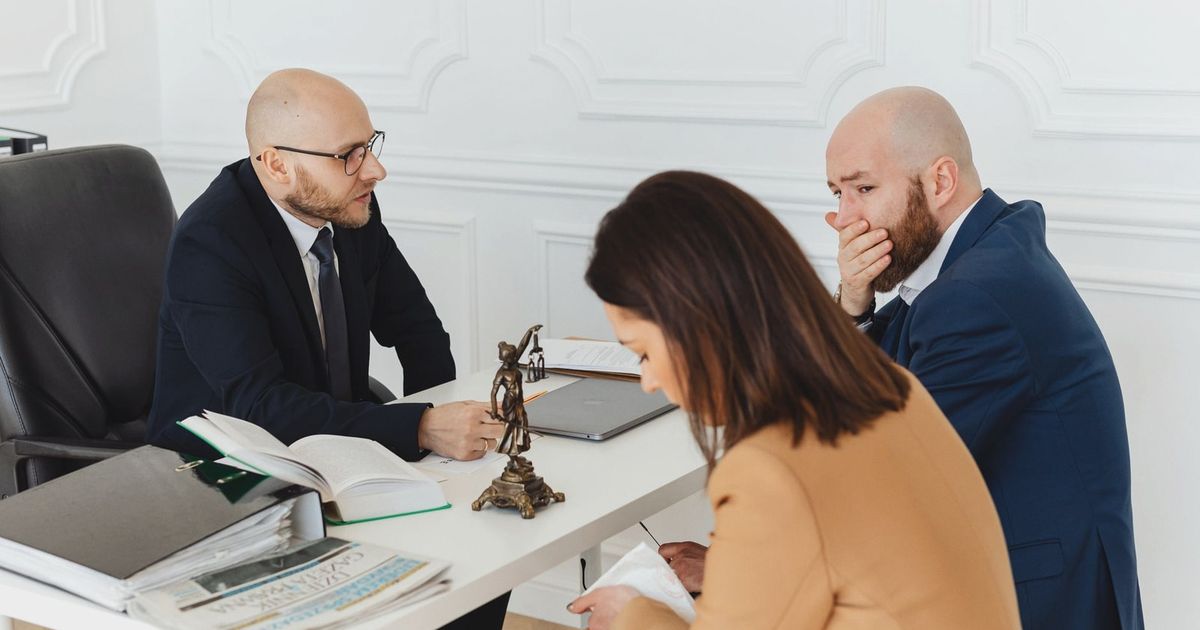 A serious legal consultation in a professional office environment involving three adults.