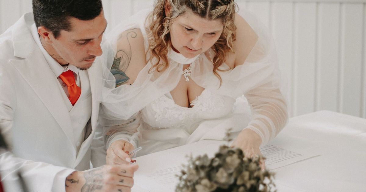 A bride and groom sign their marriage certificate during a beautiful indoor wedding ceremony.