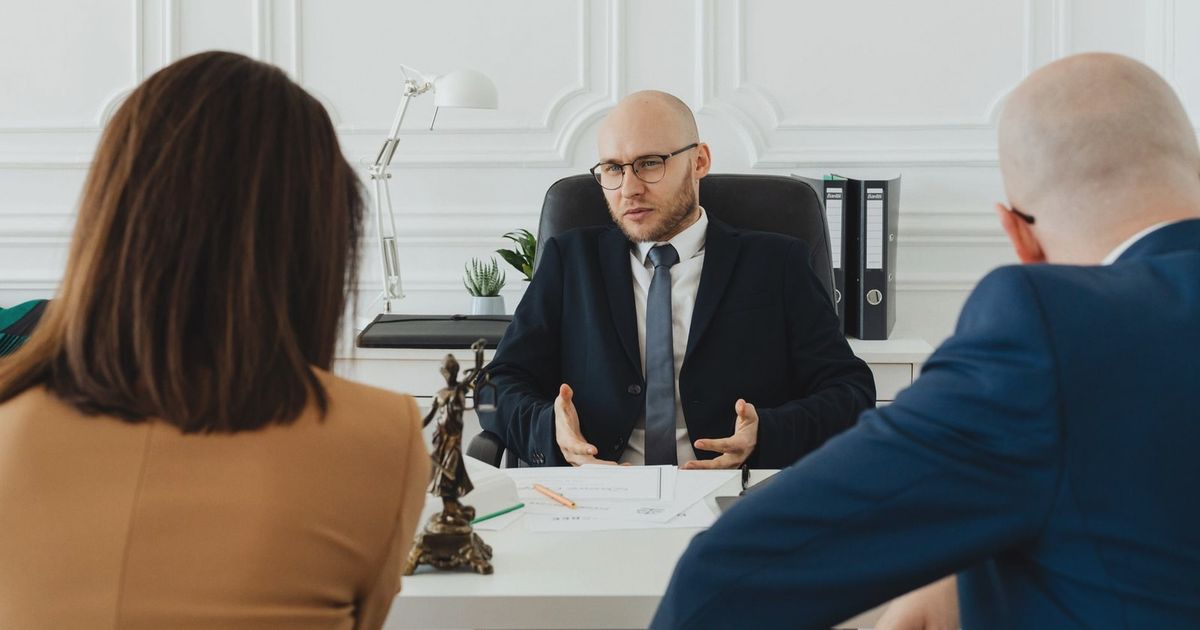 A professional business meeting with a lawyer and clients in a modern office setting.