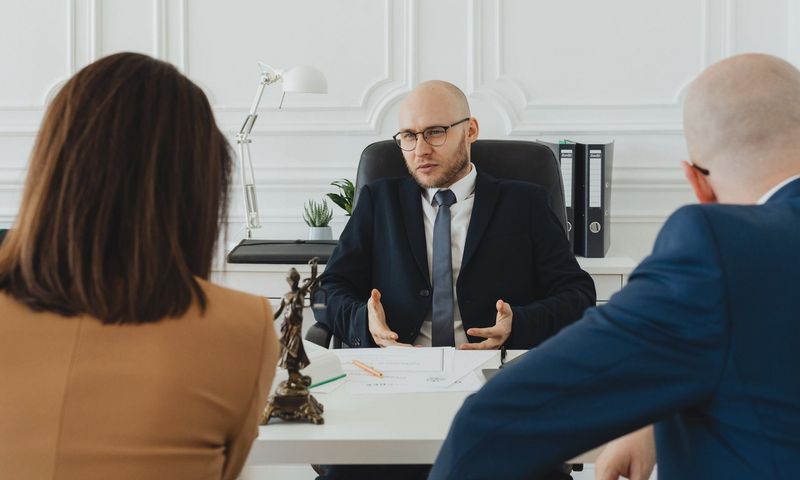 A professional business meeting with a lawyer and clients in a modern office setting.