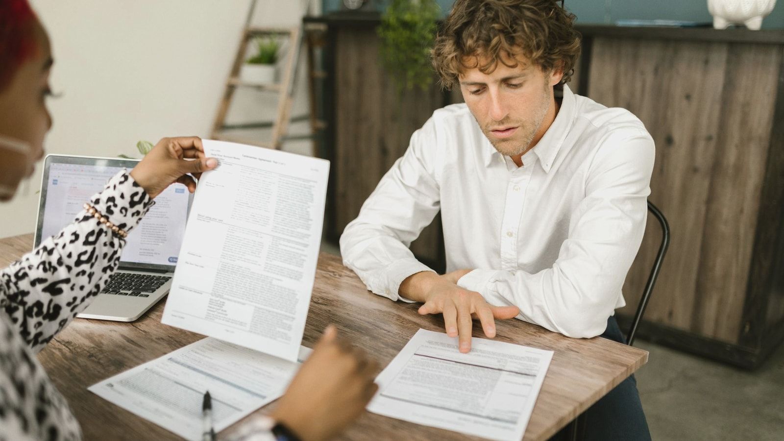 Two professionals reviewing documents in an office setting, focused on analytical tasks.